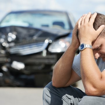 man holding his hands in front of a car accident